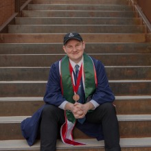 graduate in regalia sitting on stairs