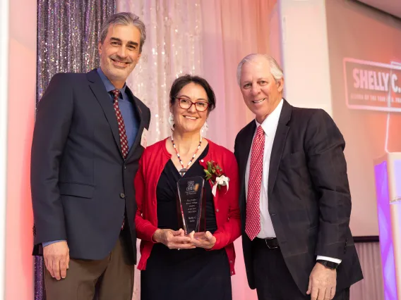 shelly lowe standing holding her award next to president robbins and dr. pollard