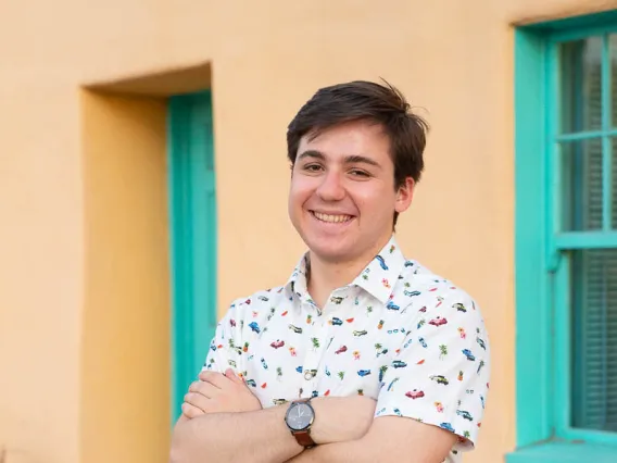 person wearing white shirt in front of yellow background, blue window frames