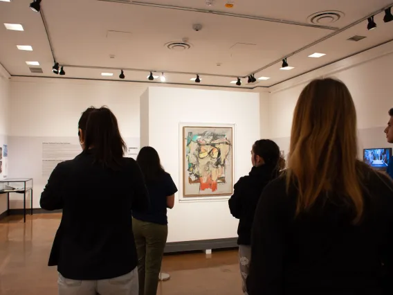 students standing looking at art with museum background