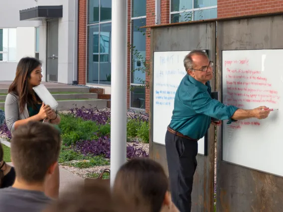 man standing in front of whiteboard teaching strudents