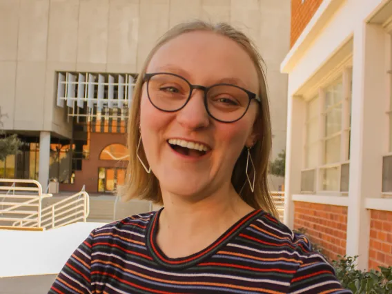 person smiling striped shirt in front of building