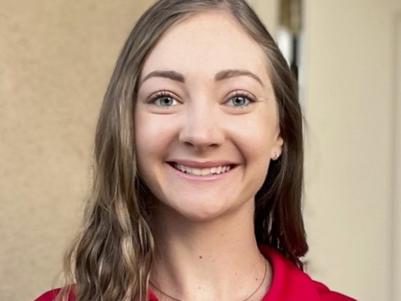 headshot of woman wearing red shirt that reads partnerships through honors