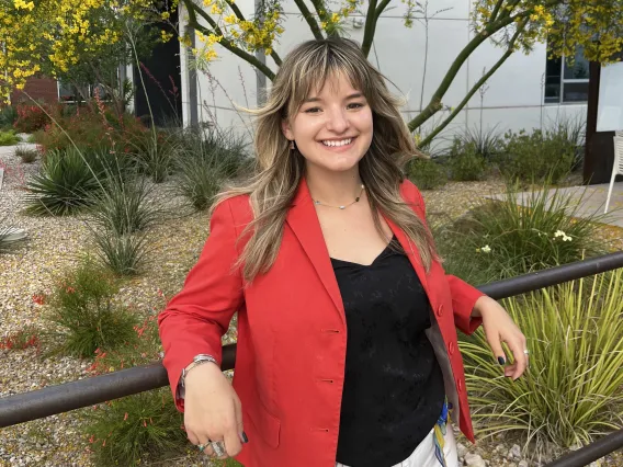 woman standing in front of yellow flowers wearing red blazer