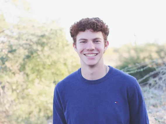 student wearing blue shirt with green background