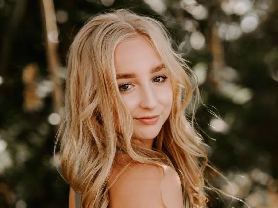 girl looking over shoulder with green tree background