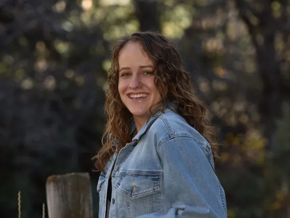 person leaning against fence wearing jean jacket