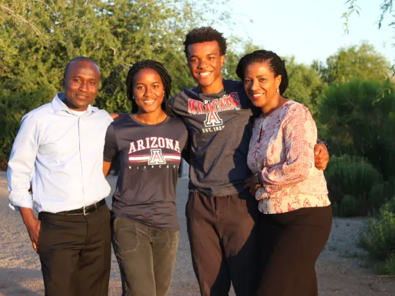 Family smiling with green trees in background