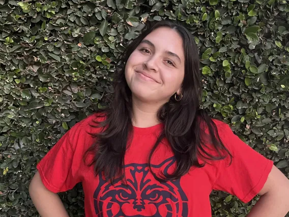 woman wearing red wildcat shirt standing in front of green leaf background