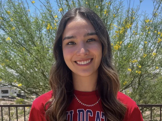 woman wearing red arizona shirt standing in front of green tree background