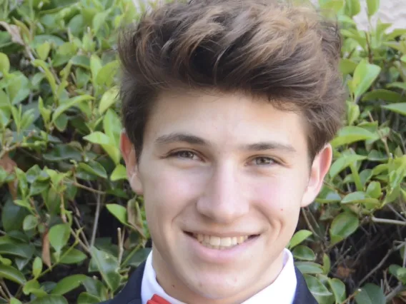 man wearing suit and red bowtie in front of green leaf background