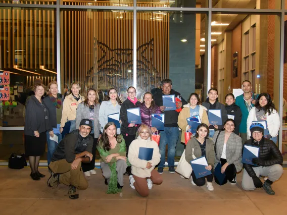 group of students and people standing in front of window holding blue folders