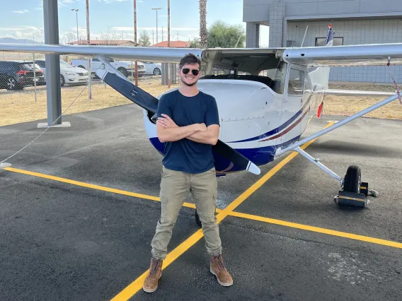 man standing with arms crossed in front of small propeller plane 