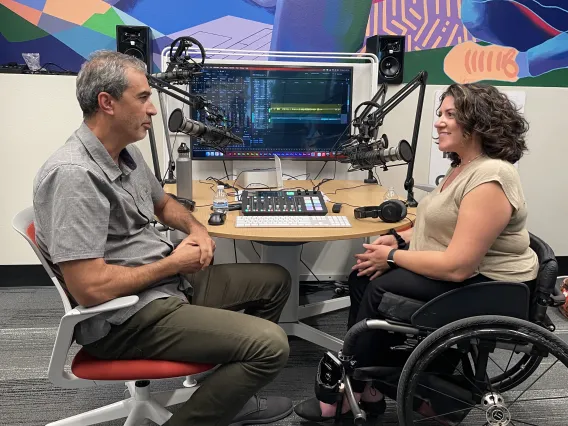 a man and a woman sitting in front of technical gear speaking into mics