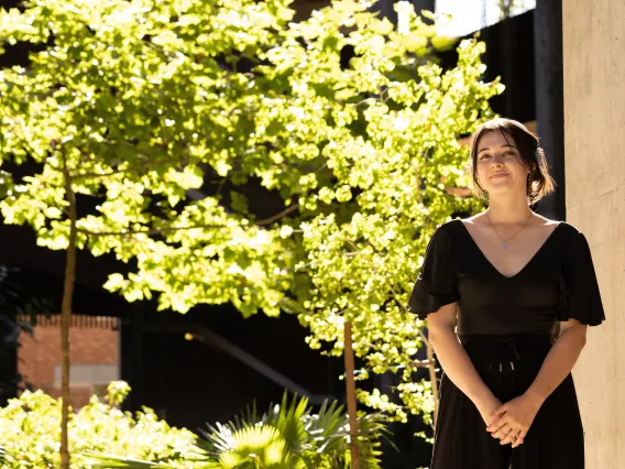 woman standing on the right in front of tree smiling at camera