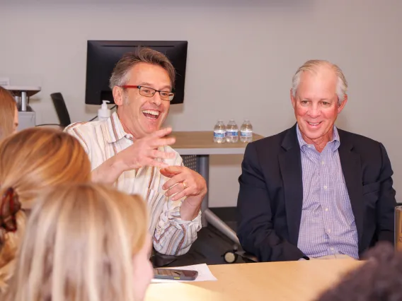 two men in class speaking to students