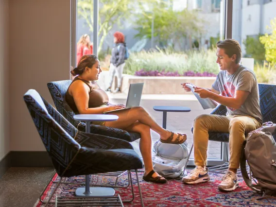 Two students meet in the Honors Village reading nook. 