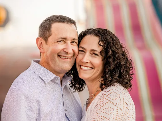 man and woman with faces close together smiling towards camera