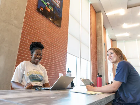 two women looking at camera sitting across from each other in lobby