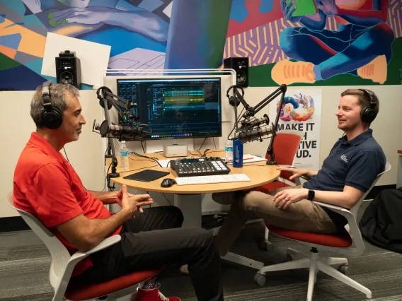 two men sitting in front of technical gear speaking into mics