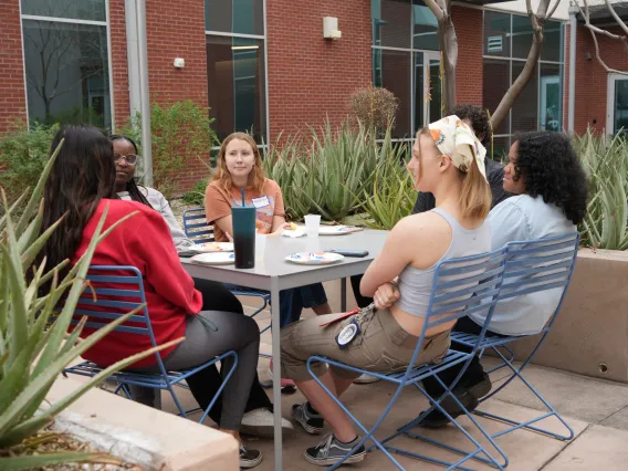 students sitting at table in courtyard