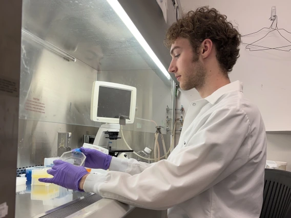 Person in white coat performing lab work