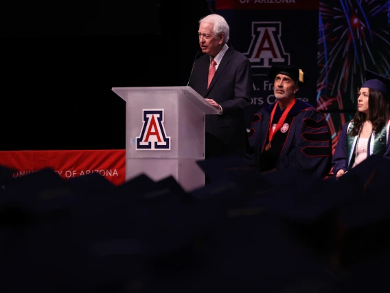 Bill Franke standing in front of graduates delivering speech