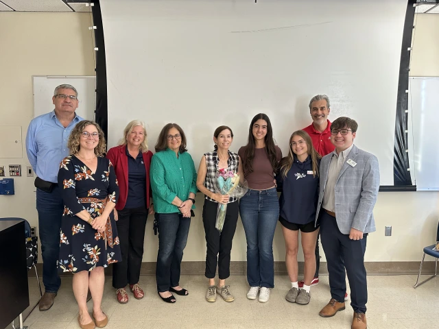 group of people smiling at camera with classroom background
