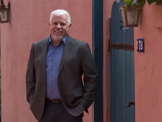 Honors Dean Terry Hunt - Standing outside by pink wall and green door