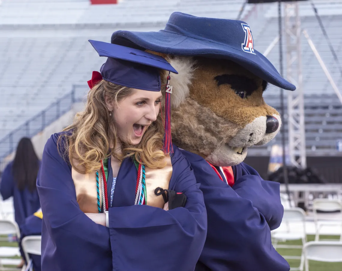 Female graduate posing with Wilbur 