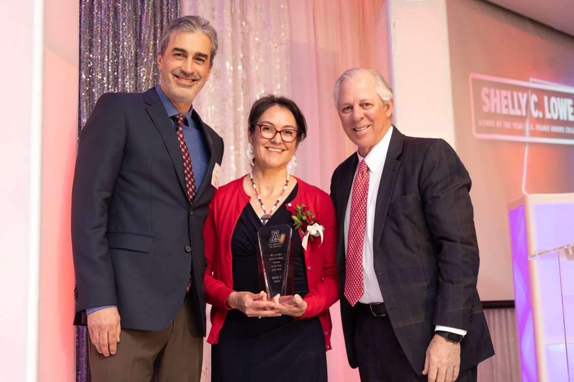 shelly lowe standing holding her award next to president robbins and dr. pollard