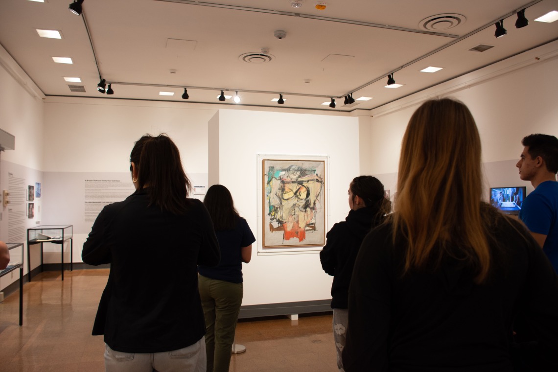 students standing looking at art with museum background