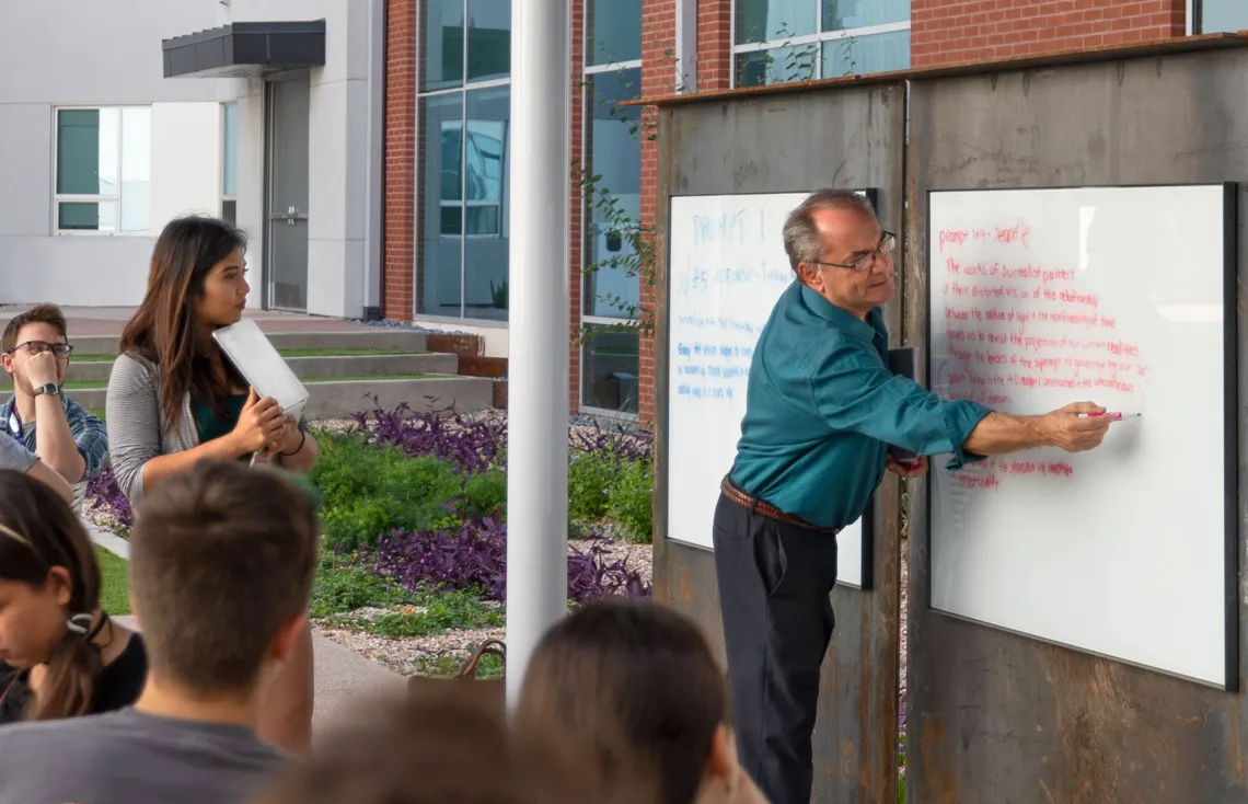 man standing in front of whiteboard teaching strudents