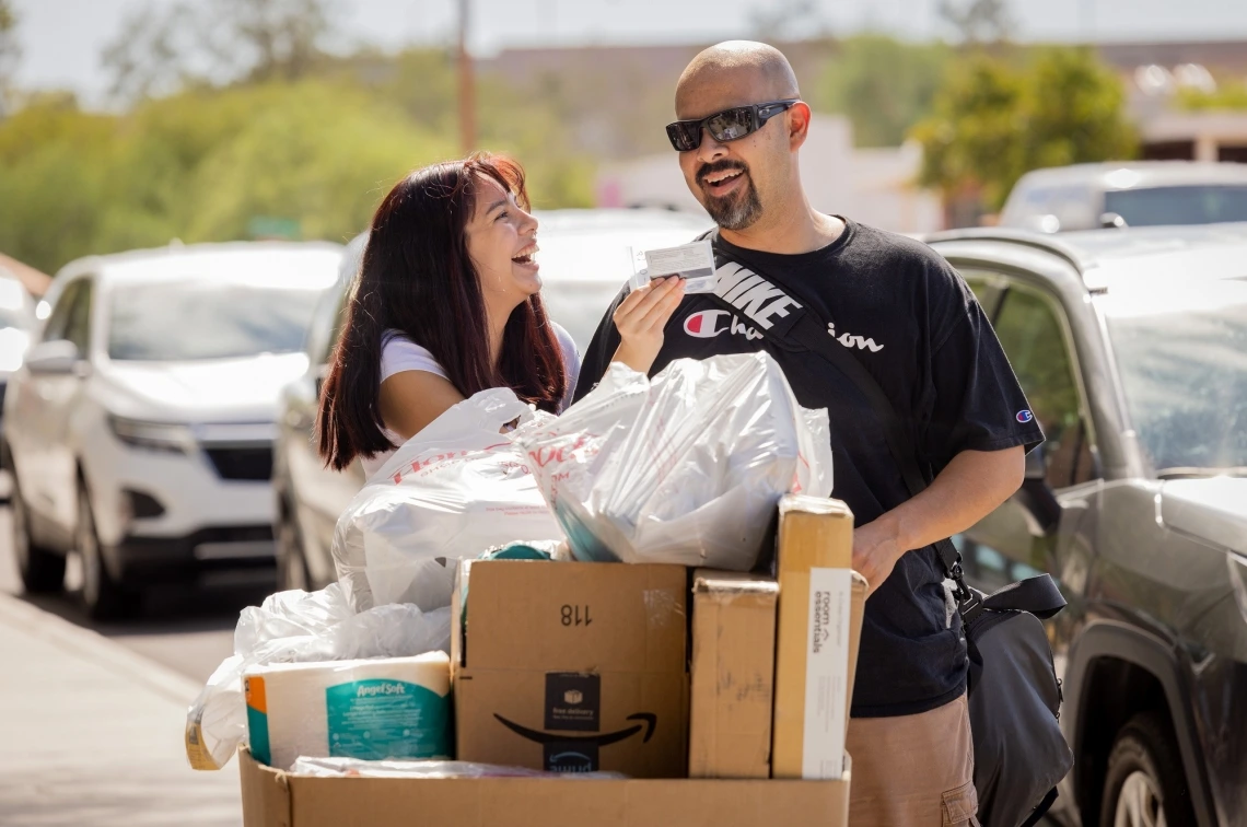 man and woman looking at cat card laughing while moving boxes