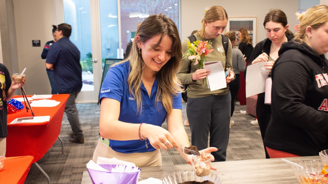 A student putting toppings on her treat during a monthly event.
