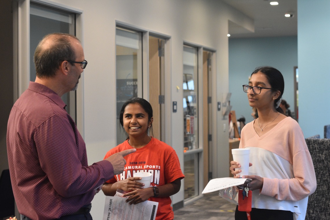 Two students talking with an advisor.