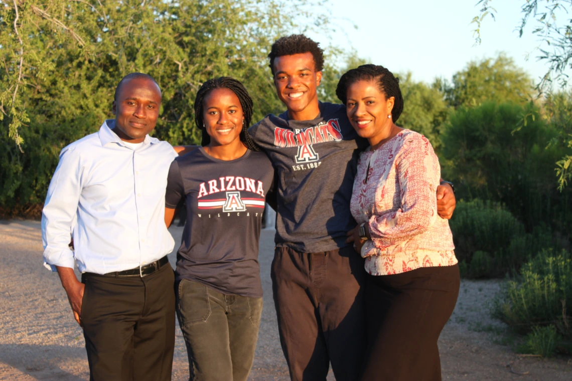 Family smiling with green trees in background