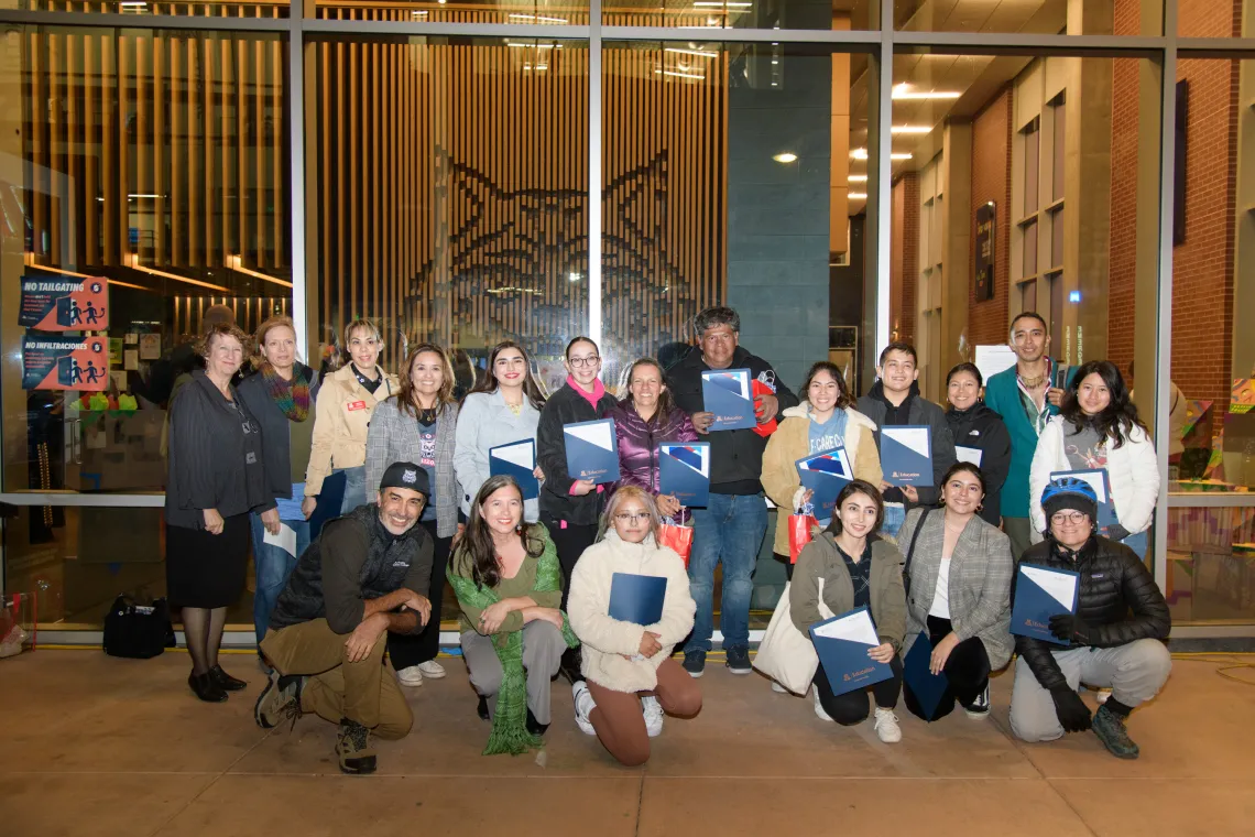 group of students and people standing in front of window holding blue folders