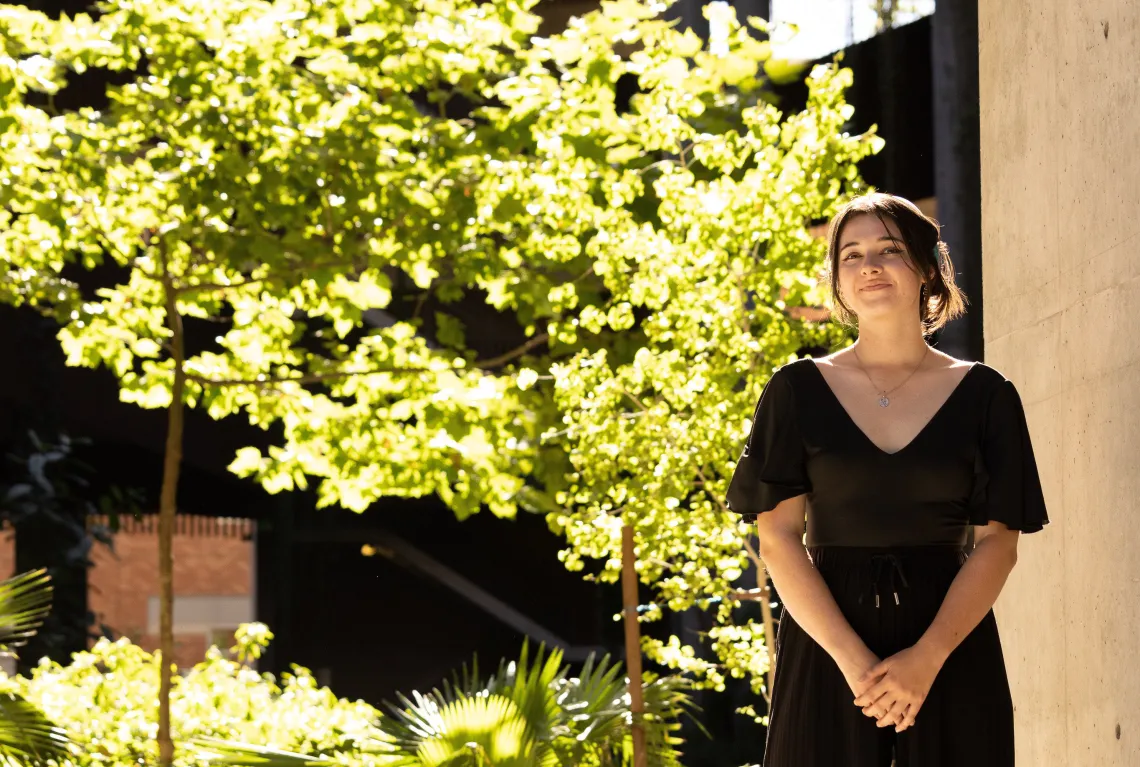 woman standing on the right in front of tree smiling at camera