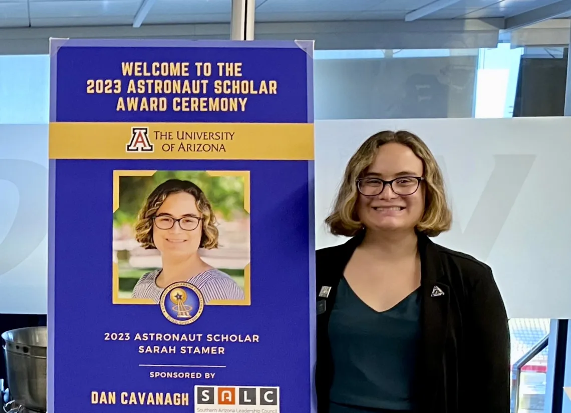 student standing next to sign 