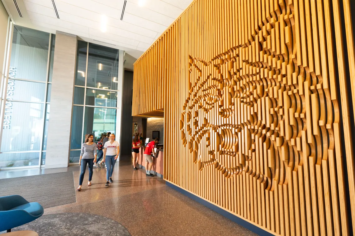 Students walking past the wildcat wall in the Honors Village