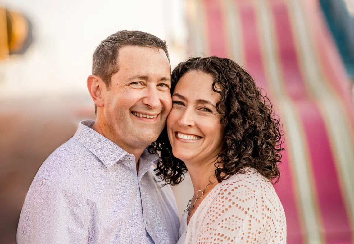 man and woman with faces close together smiling towards camera