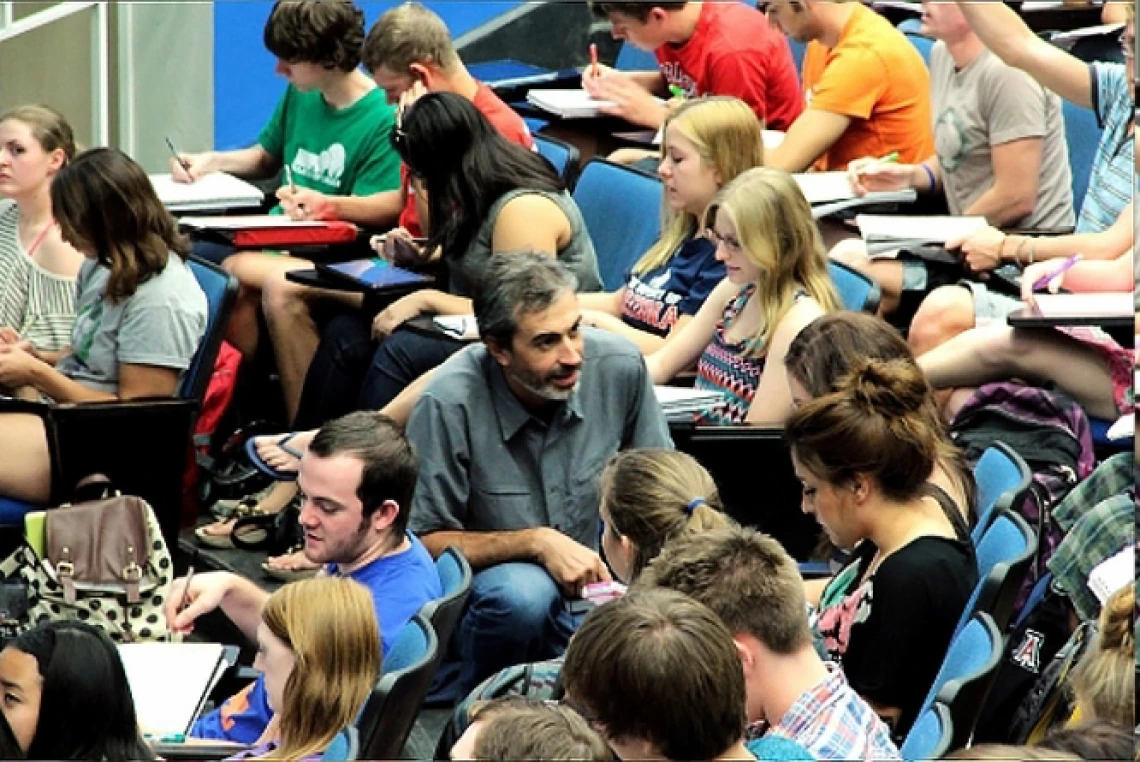 man in crowd of students in lecture hall teaching