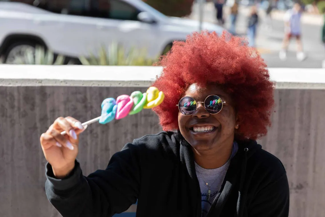 Student sitting outside eating colorful candy.