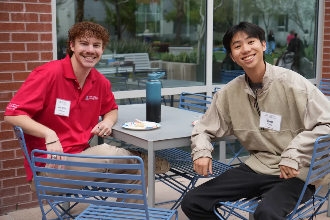 two students at table smiling at camera