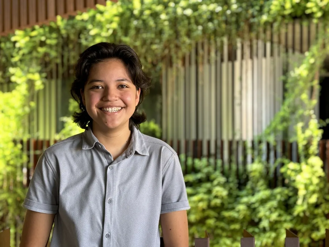 student in front of green background smiling at camera