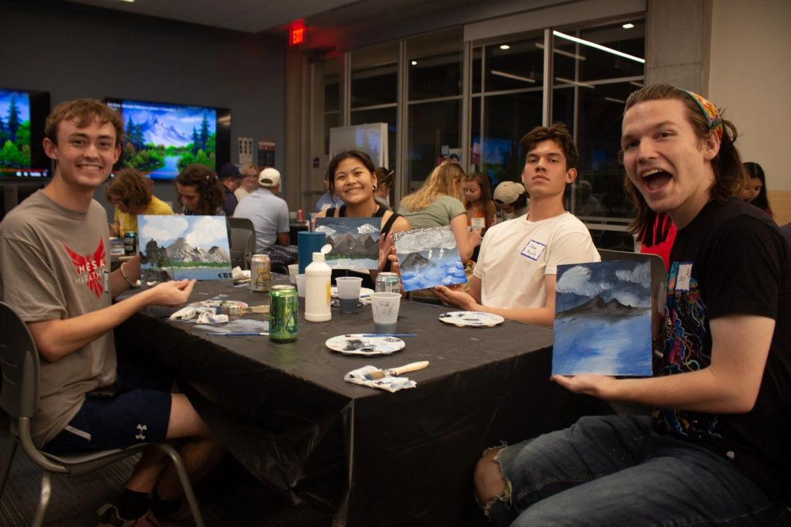 Students holding their paintings they made