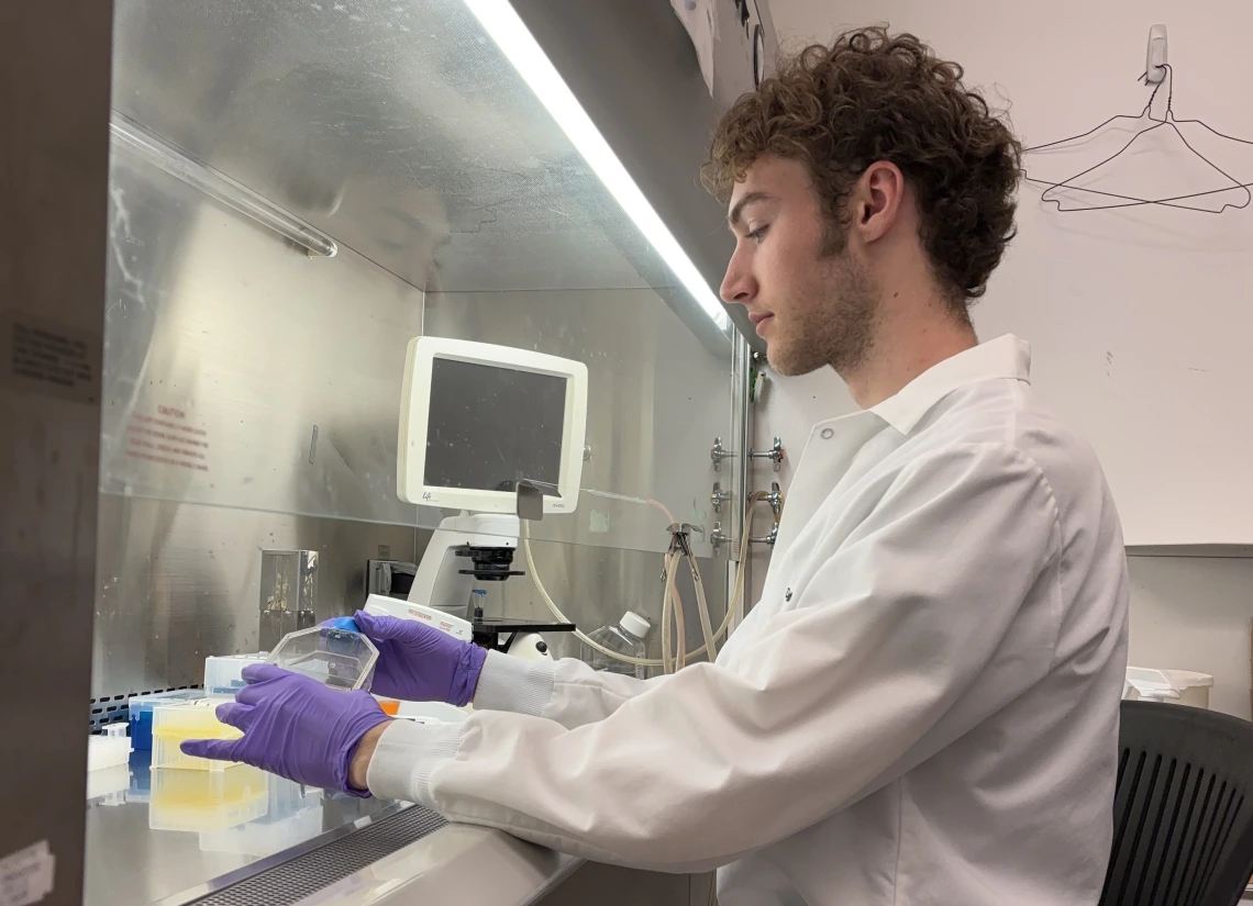 Person in white coat performing lab work