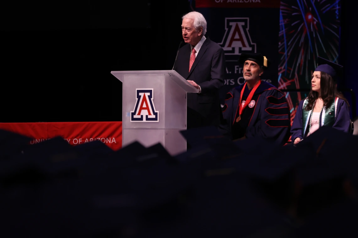 Bill Franke standing in front of graduates delivering speech