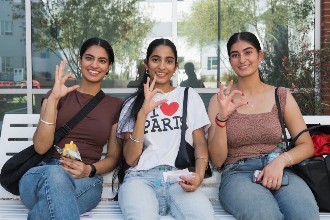 Three students giving WG sign